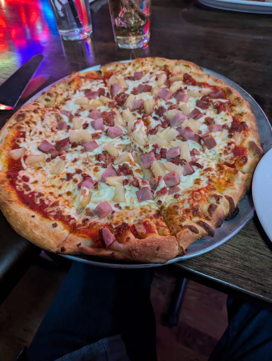 A ham and pineapple pizza on a metal tray